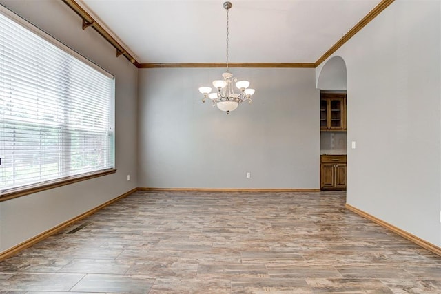 3401 Fox Hill Ter, Edmond, OK 73034 - unfurnished room with crown molding, a chandelier, arched walkways, and light wood-style floors