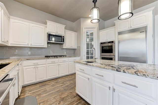3401 Fox Hill Ter, Edmond, OK 73034 - kitchen featuring stainless steel appliances, light wood-style floors, tasteful backsplash, hanging light fixtures, and white cabinets