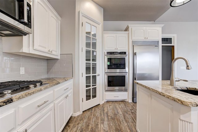 3401 Fox Hill Ter, Edmond, OK 73034 - kitchen with appliances with stainless steel finishes, light wood-style flooring, white cabinets, and tasteful backsplash
