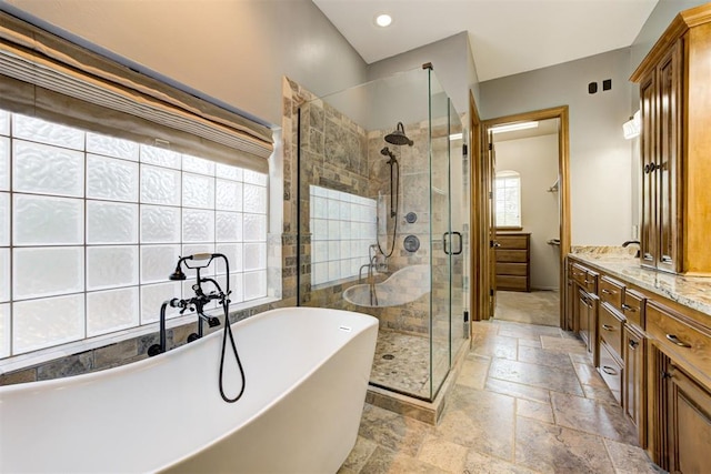 3401 Fox Hill Ter, Edmond, OK 73034 - bathroom with stone tile floors, a freestanding bath, double vanity, a shower stall, and recessed lighting