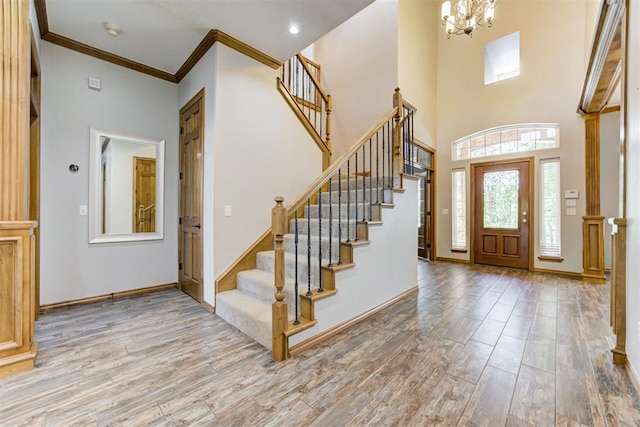 3401 Fox Hill Ter, Edmond, OK 73034 - foyer featuring stairway, wood finished floors, a chandelier, a towering ceiling, and crown molding
