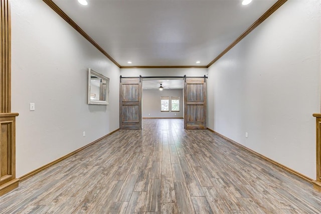 3401 Fox Hill Ter, Edmond, OK 73034 - unfurnished living room with a barn door, ornamental molding, light wood-style floors, and recessed lighting