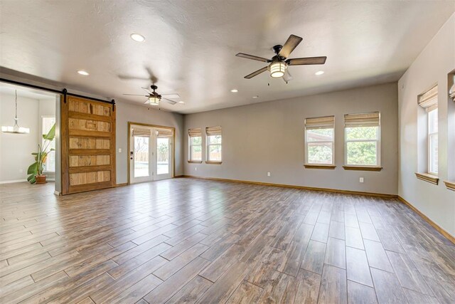 3401 Fox Hill Ter, Edmond, OK 73034 - unfurnished room featuring a barn door, a ceiling fan, wood finished floors, and recessed lighting