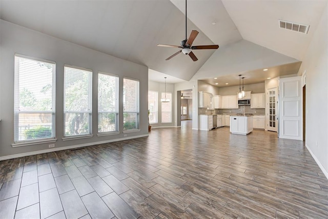 3401 Fox Hill Ter, Edmond, OK 73034 - unfurnished living room featuring ceiling fan, healthy amount of natural light, wood finished floors, and high vaulted ceiling