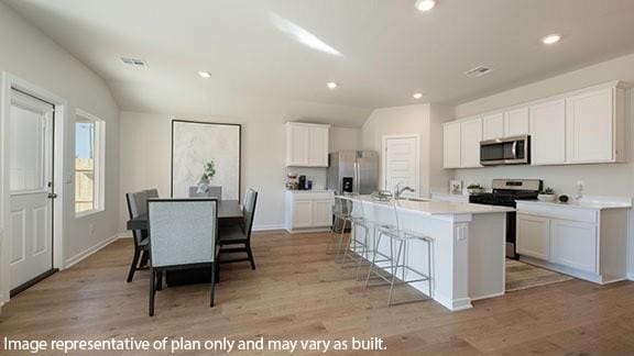 2504 Kathleens Xing, Yukon, OK 73099 - kitchen with stainless steel appliances, a kitchen breakfast bar, white cabinets, an island with sink, and lofted ceiling