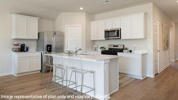 2504 Kathleens Xing, Yukon, OK 73099 - kitchen featuring appliances with stainless steel finishes, a sink, light wood-style flooring, a breakfast bar, and white cabinets