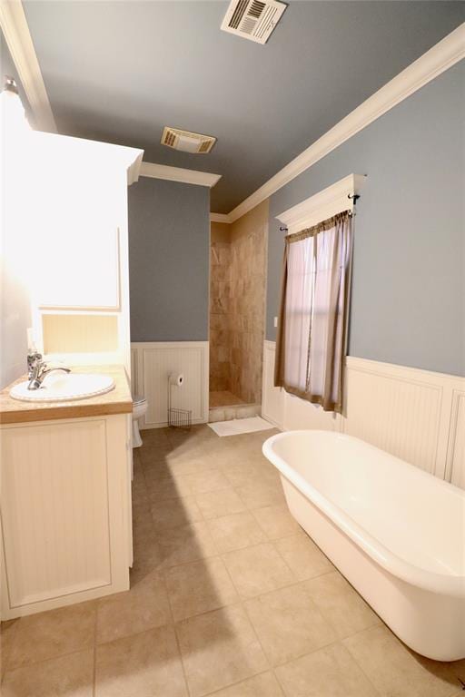 bathroom with a wainscoted wall, a shower stall, ornamental molding, a freestanding bath, and vanity