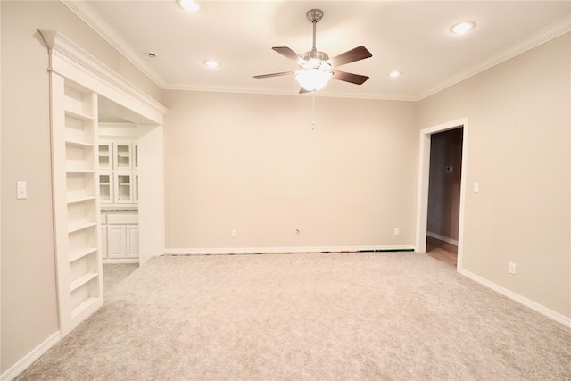 spare room with ceiling fan, light colored carpet, recessed lighting, crown molding, and baseboards