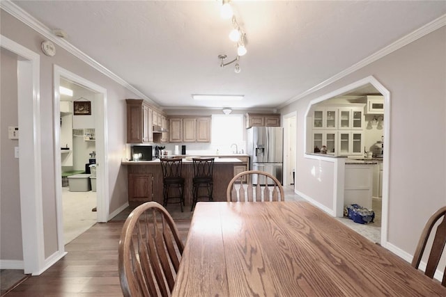 dining room with baseboards, ornamental molding, and wood finished floors