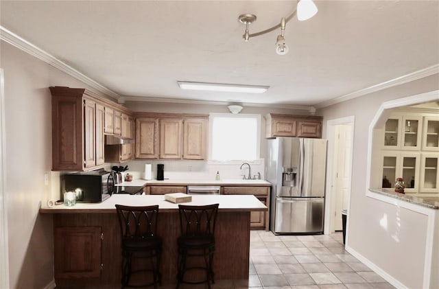 kitchen with stainless steel appliances, a peninsula, light countertops, a sink, and crown molding