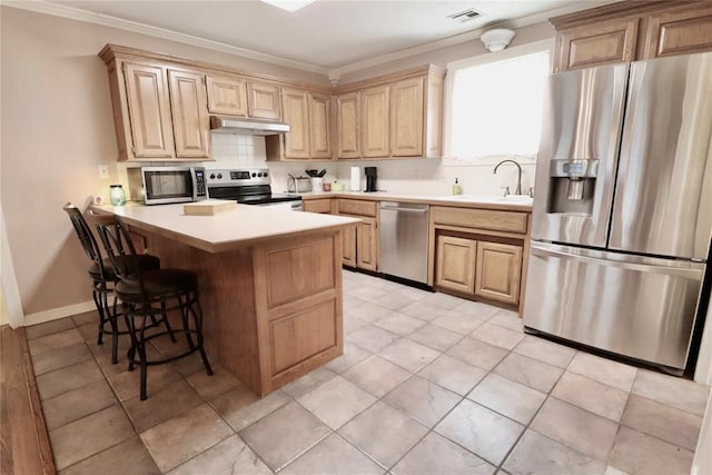 kitchen with appliances with stainless steel finishes, a sink, a peninsula, a breakfast bar area, and crown molding