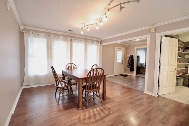 dining room with crown molding, light wood finished floors, and baseboards