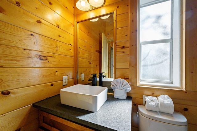 bathroom with wood walls, vanity, and toilet
