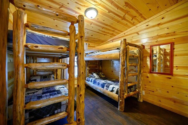 bedroom with wooden walls, lofted ceiling, wood-type flooring, and wooden ceiling