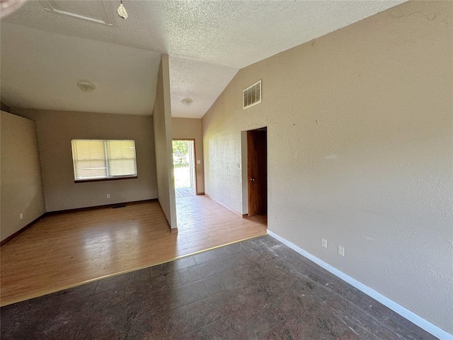 spare room with baseboards, lofted ceiling, and a textured ceiling