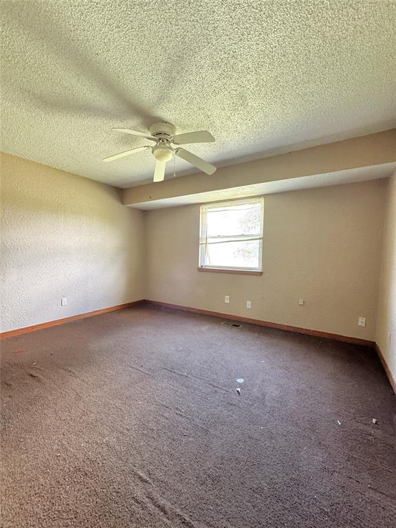 carpeted spare room with baseboards, a ceiling fan, and a textured ceiling