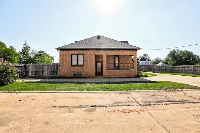 100 S Macomb Ave, El Reno, OK 73036 - rear view of property featuring brick siding, fence, covered porch, and driveway