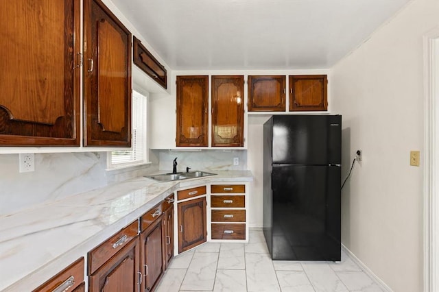 2545 W Eubanks St, Oklahoma City, OK 73112 - kitchen with freestanding refrigerator, light marble finish flooring, a sink, and decorative backsplash