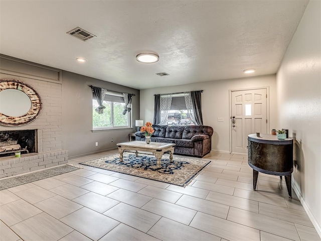 living area featuring baseboards, a brick fireplace, and light tile patterned floors