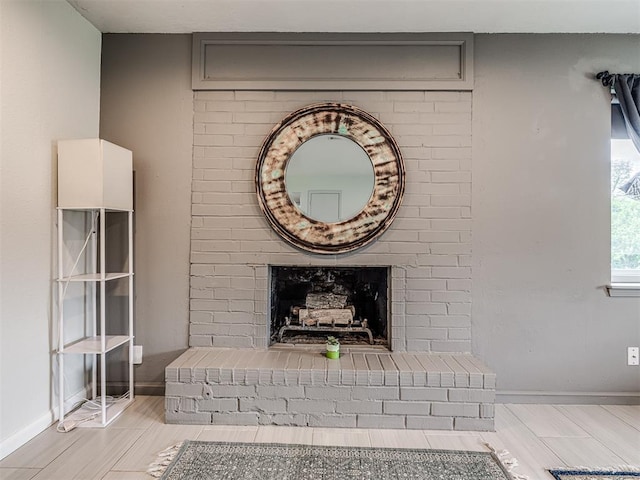 detailed view of a fireplace, wood finished floors, and baseboards