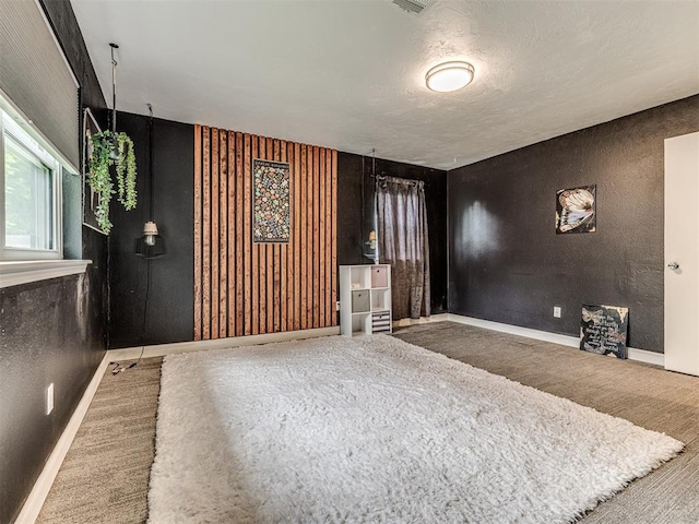 unfurnished living room featuring carpet floors, baseboards, and a textured wall