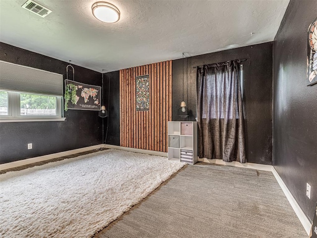 spare room featuring carpet floors, a textured ceiling, and baseboards