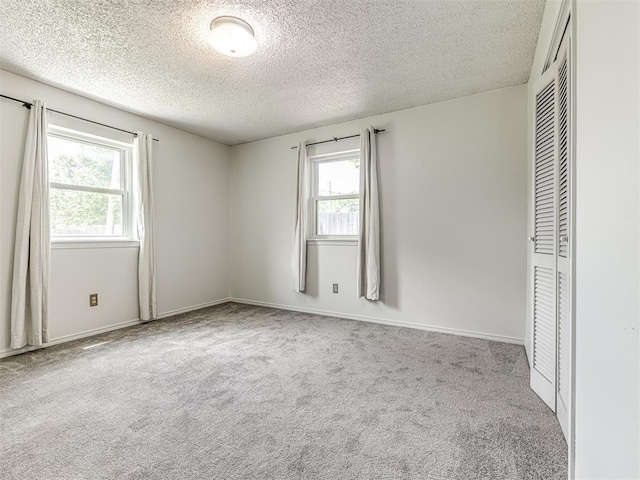 unfurnished bedroom with a textured ceiling, carpet floors, a closet, and baseboards