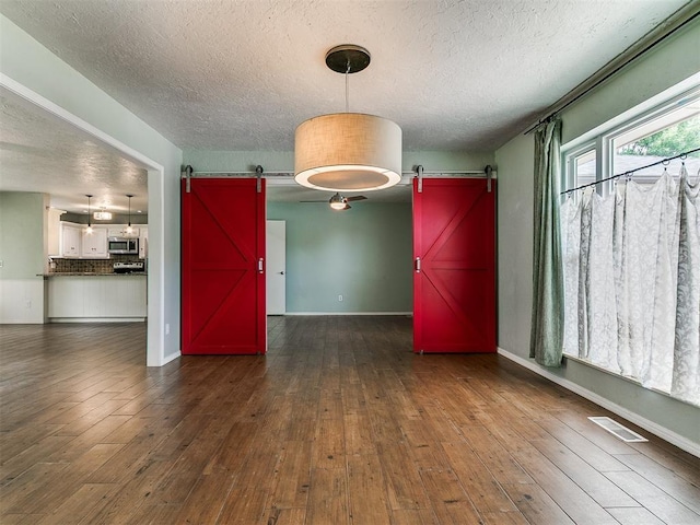 2916 Prairie Rose Ct, Oklahoma City, OK 73120 - spare room with a barn door, a textured ceiling, and hardwood / wood-style flooring