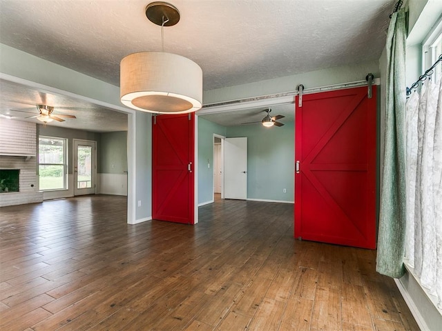 2916 Prairie Rose Ct, Oklahoma City, OK 73120 - empty room with a barn door, ceiling fan, hardwood / wood-style floors, baseboards, and a textured ceiling