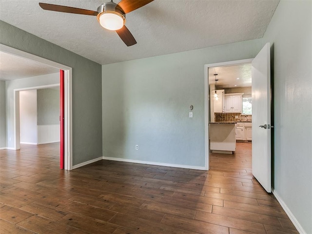 2916 Prairie Rose Ct, Oklahoma City, OK 73120 - unfurnished room with a ceiling fan, dark wood finished floors, a textured ceiling, and baseboards