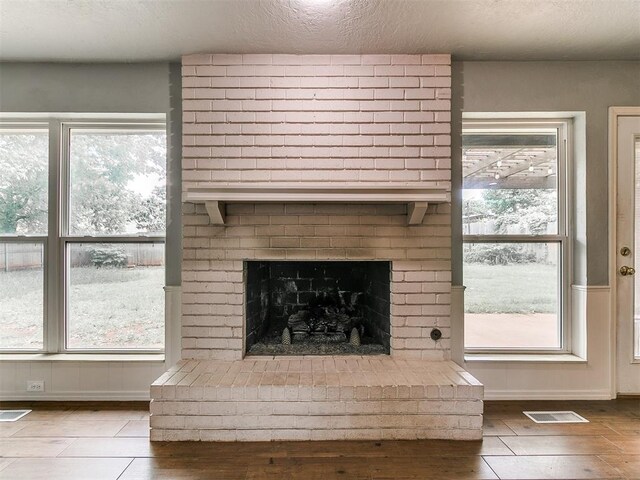 2916 Prairie Rose Ct, Oklahoma City, OK 73120 - detailed view of wood finished floors, a brick fireplace, a textured ceiling, and baseboards