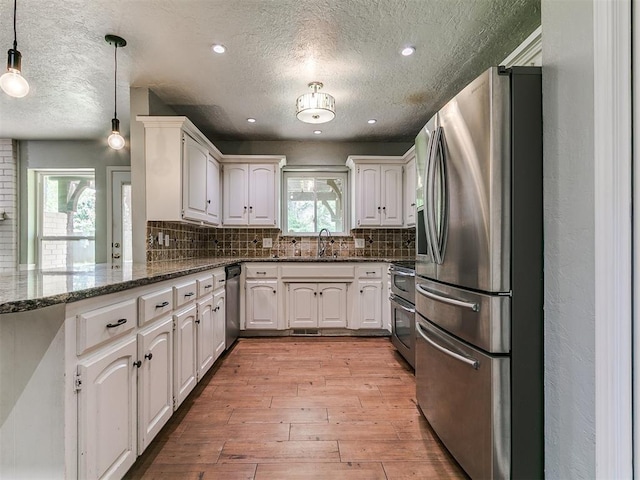2916 Prairie Rose Ct, Oklahoma City, OK 73120 - kitchen with appliances with stainless steel finishes, light wood finished floors, a textured ceiling, tasteful backsplash, and pendant lighting