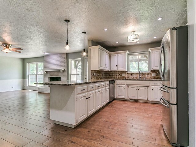 2916 Prairie Rose Ct, Oklahoma City, OK 73120 - kitchen with appliances with stainless steel finishes, open floor plan, a peninsula, tasteful backsplash, and a textured ceiling