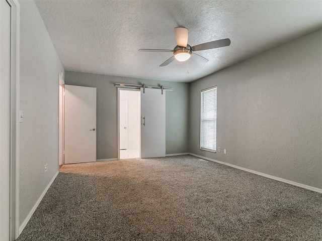 2916 Prairie Rose Ct, Oklahoma City, OK 73120 - carpeted empty room with a textured ceiling, ceiling fan, a textured wall, baseboards, and a barn door