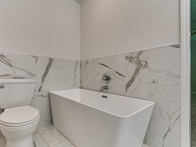 2916 Prairie Rose Ct, Oklahoma City, OK 73120 - bathroom with marble look tiles, tile walls, toilet, a freestanding bath, and wainscoting