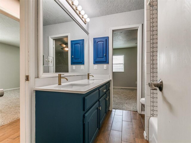 2916 Prairie Rose Ct, Oklahoma City, OK 73120 - full bathroom with a textured ceiling, hardwood / wood-style flooring, toilet, double vanity, and baseboards