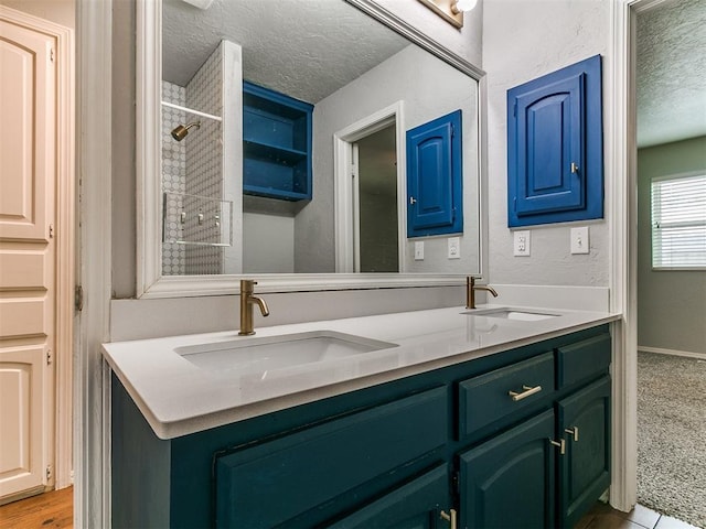 2916 Prairie Rose Ct, Oklahoma City, OK 73120 - bathroom with a textured ceiling, double vanity, and tiled shower