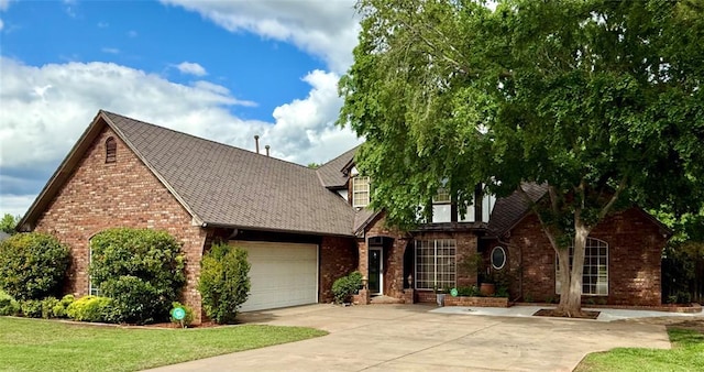 view of front facade with brick siding, an attached garage, driveway, roof with shingles, and a front yard