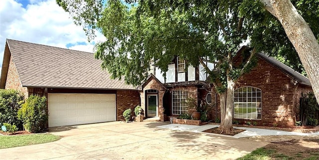 view of front facade featuring brick siding, driveway, a garage, and a shingled roof