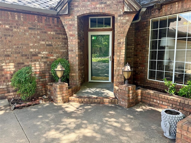 entrance to property with brick siding and a patio area