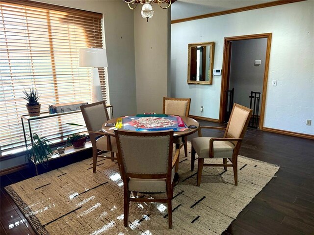 dining space featuring baseboards, wood finished floors, crown molding, a chandelier, and healthy amount of natural light