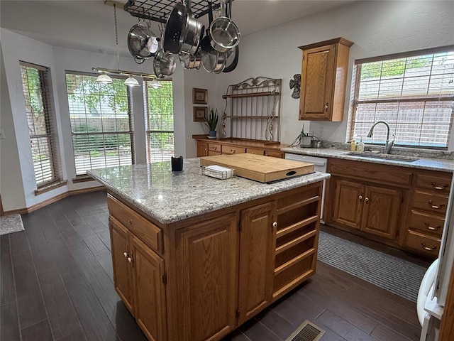 kitchen featuring a sink, dark wood-style floors, a center island, and brown cabinets