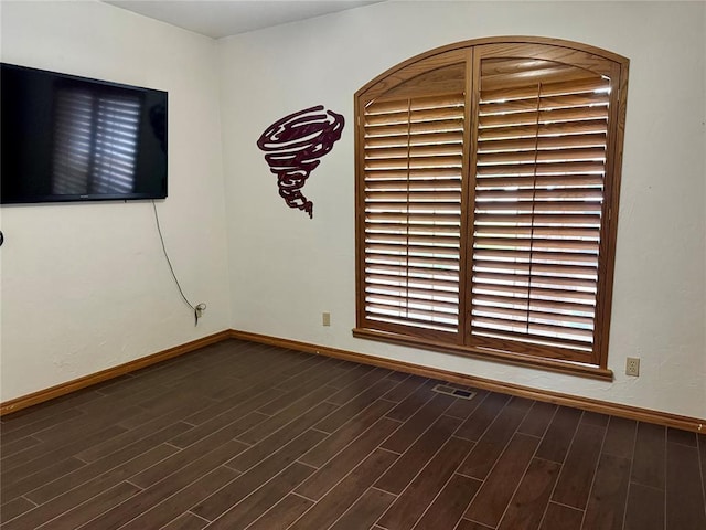 unfurnished room featuring baseboards and dark wood-style floors