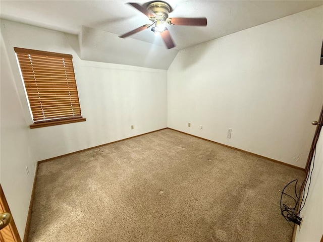 spare room featuring a ceiling fan, carpet flooring, lofted ceiling, and baseboards