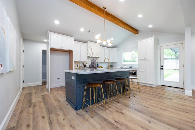 2101 NW 60th St, Oklahoma City, OK 73112 - kitchen featuring white cabinetry, light wood-type flooring, pendant lighting, a kitchen breakfast bar, and a kitchen island with sink
