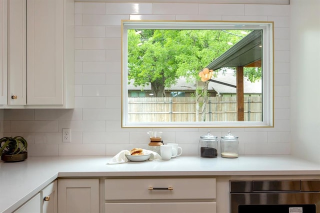 2101 NW 60th St, Oklahoma City, OK 73112 - kitchen featuring stainless steel oven, backsplash, white cabinets, light countertops, and plenty of natural light