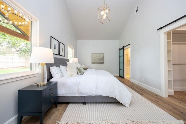 2101 NW 60th St, Oklahoma City, OK 73112 - bedroom with a barn door, wood finished floors, high vaulted ceiling, baseboards, and a chandelier