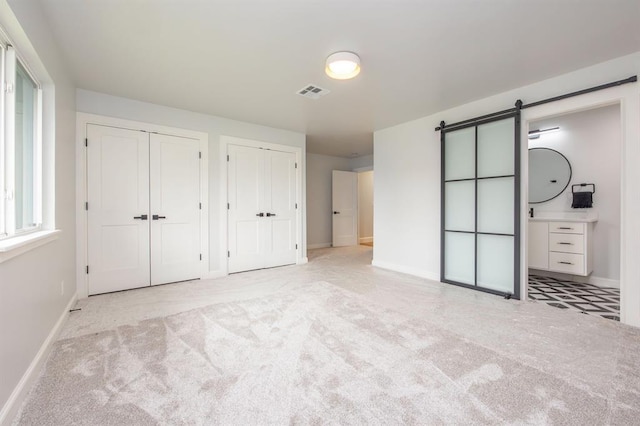 2101 NW 60th St, Oklahoma City, OK 73112 - unfurnished bedroom with two closets, a barn door, baseboards, and carpet floors