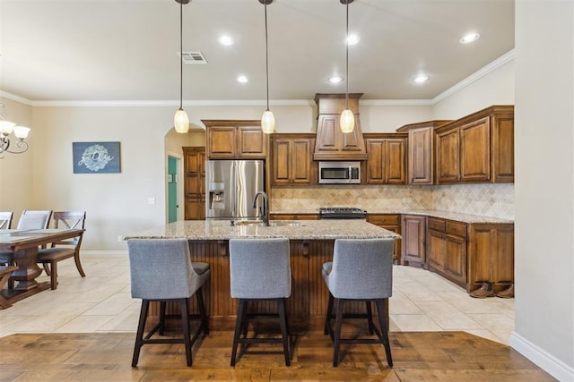 19724 Meadow Bend Ave, Edmond, OK 73012 - kitchen with appliances with stainless steel finishes, a sink, decorative backsplash, light stone counters, and a kitchen island with sink