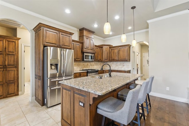 19724 Meadow Bend Ave, Edmond, OK 73012 - kitchen featuring stainless steel appliances, a sink, arched walkways, light stone counters, and recessed lighting